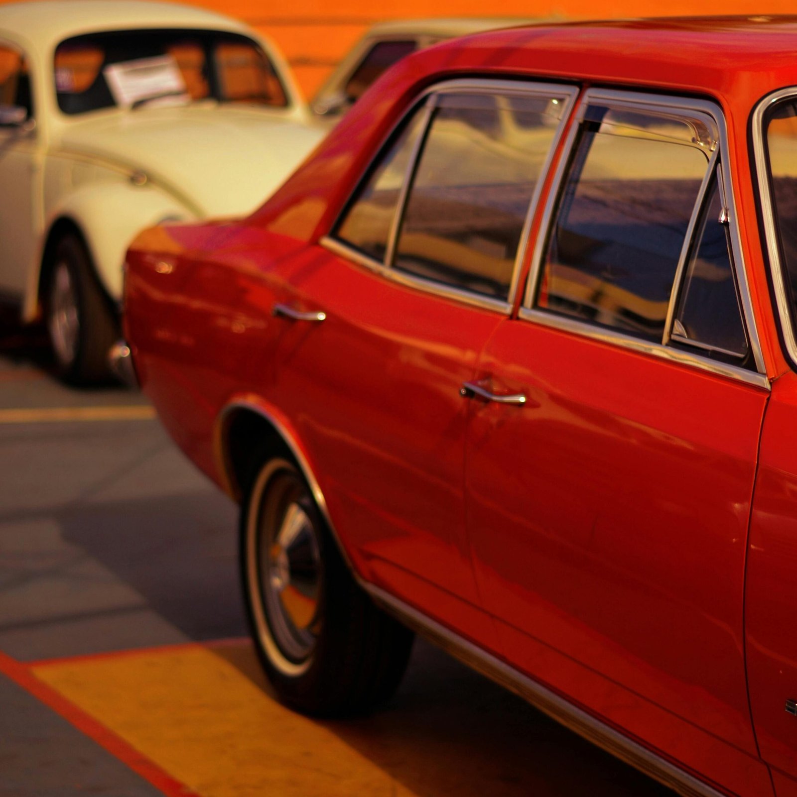 Classic vintage cars parked on an urban street, beautifully lit by the warm glow of sunset.